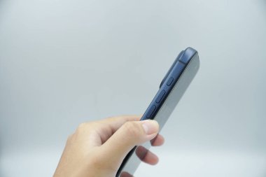 Bir sol el iPhone 17 Pro derin mavi varyant tutar ve yanında beyaz arkaplan ile ses düğmelerini gösterir.