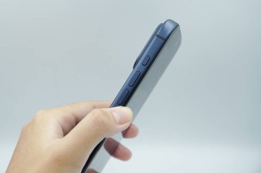 Bir sol el iPhone 17 Pro derin mavi varyant tutar ve yanında beyaz arkaplan ile ses düğmelerini gösterir.