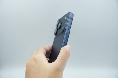 Bir sol el iPhone 17 Pro derin mavi varyant tutar ve yanında beyaz arkaplan ile ses düğmelerini gösterir.