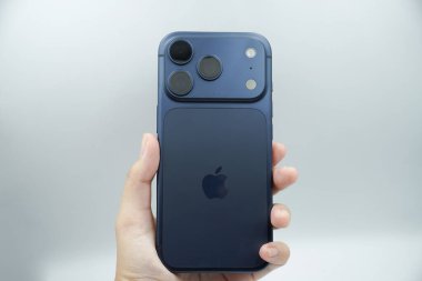 iPhone 17 'nin arkasını gösteren bir el. 3 kameralı derin mavi varyant.