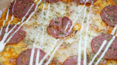 Pizzanın ortasında sucuklu biftek, mozzarella peyniri ve mayonez var..