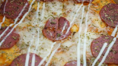 Pizzanın ortasında sucuklu biftek, mozzarella peyniri ve mayonez var..