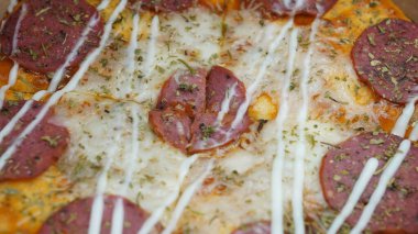 Pizzanın ortasında sucuklu biftek, mozzarella peyniri ve mayonez var..