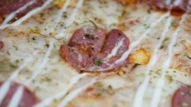 Pizzanın ortasında sucuklu biftek, mozzarella peyniri ve mayonez var..