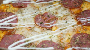 Pizzanın ortasında sucuklu biftek, mozzarella peyniri ve mayonez var..