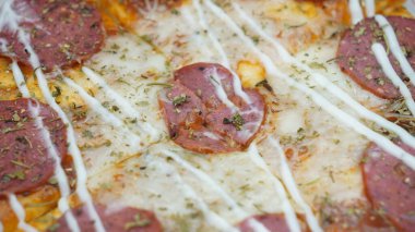 Pizzanın ortasında sosis, mozarella peyniri ve mayonez var.