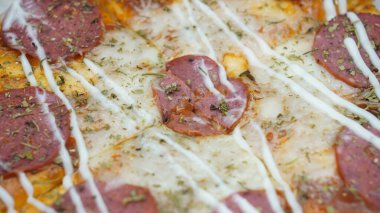 Pizzanın ortasında sosis, mozarella peyniri ve mayonez var.