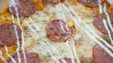 Pizzanın ortasında sosis, mozarella peyniri ve mayonez var.