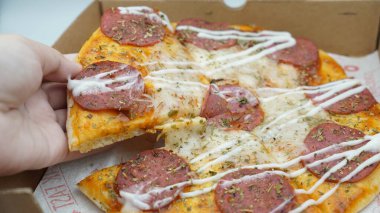 Bir dilim sosisli pizza çekildiğinde esneyen Mozzarella peyniri.