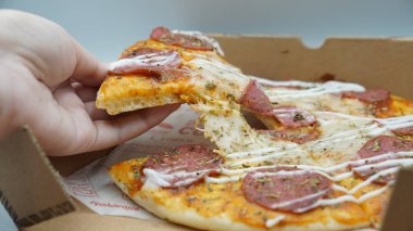 Bir dilim sosisli pizza çekildiğinde esneyen Mozzarella peyniri.