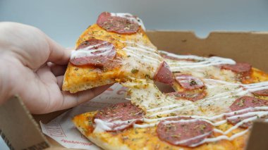 Bir dilim sosisli pizza çekildiğinde esneyen Mozzarella peyniri.