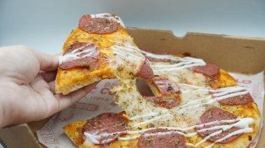 Bir dilim sosisli pizza çekildiğinde esneyen Mozzarella peyniri.