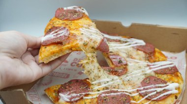 Bir dilim sosisli pizza çekildiğinde esneyen Mozzarella peyniri.