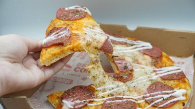 Bir dilim sosisli pizza çekildiğinde esneyen Mozzarella peyniri.