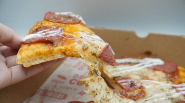 Bir dilim sosisli pizza çekildiğinde esneyen Mozzarella peyniri.