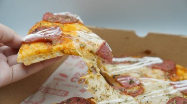 Bir dilim sosisli pizza çekildiğinde esneyen Mozzarella peyniri.