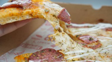 Bir dilim sosisli pizza çekildiğinde esneyen Mozzarella peyniri.