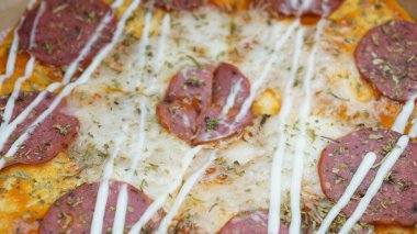 Pizzanın ortasında sosis, mozarella peyniri ve mayonez var.