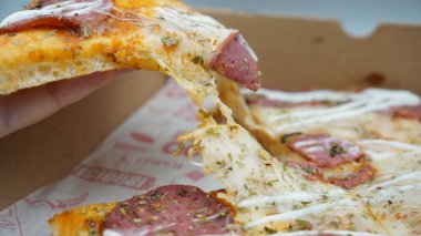 Bir dilim sosisli pizza çekildiğinde esneyen Mozzarella peyniri.