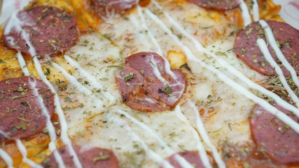 Pizzanın ortasında sosis, mozarella peyniri ve mayonez var.