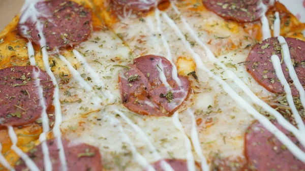 Pizzanın ortasında sosis, mozarella peyniri ve mayonez var.