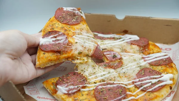 Bir dilim sosisli pizza çekildiğinde esneyen Mozzarella peyniri.