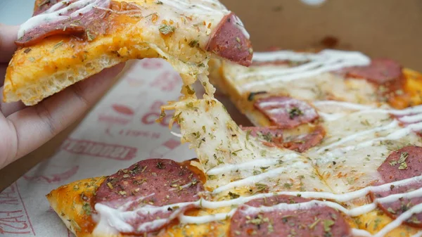 Bir dilim sosisli pizza çekildiğinde esneyen Mozzarella peyniri.