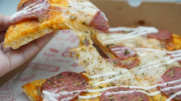 Bir dilim sosisli pizza çekildiğinde esneyen Mozzarella peyniri.