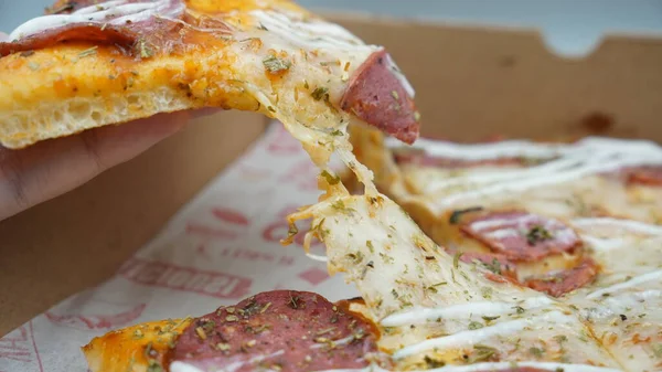 Bir dilim sosisli pizza çekildiğinde esneyen Mozzarella peyniri.