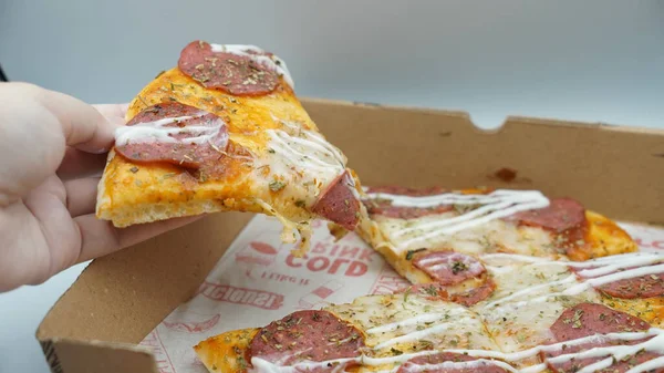 Bir dilim sosisli pizza çekildiğinde esneyen Mozzarella peyniri.