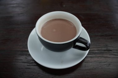 Bir fincan sıcak çikolata siyah bir fincanda ve siyah bir ahşap masada servis edilir..