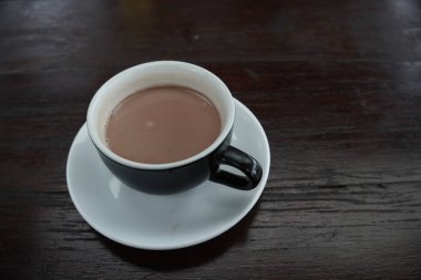 Bir fincan sıcak çikolata siyah bir fincanda ve siyah bir ahşap masada servis edilir..