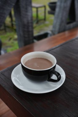 Bir fincan sıcak çikolata siyah bir fincanda ve siyah bir ahşap masada servis edilir..