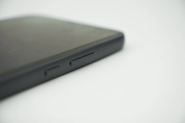 Beyaz arkaplanda açma kapama düğmesi olan parlak siyah bir akıllı telefonun yan tarafı..