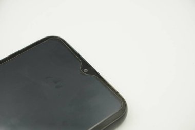 Beyaz arka planı olan siyah bir akıllı telefonun ön kamerası.