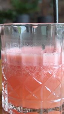 Kadın meyve sıkacağını renkli arka planda cama dolduruyor, turunçgiller kafede sağlıklı taze meyve suyu, sabah kahvaltısı içeceği. Yüksek kalite 4k görüntü