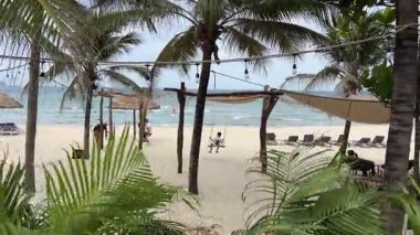 Phu Quoc Adası 'nda çocukların palmiye ağaçlarının altında sallanmaktan hoşlandıkları tropik bir plaj. Hamaklar rüzgarda sallanıyor, dalgalar okyanusta parıldıyor ve çok az insan cennette dinleniyor.. 