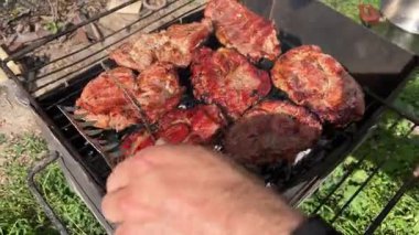 Güneşli bir günde, açık ateşte domuz eti pişirirken ve pişirirken, yaz barbeküsünde açık ateşte domuz eti pişirirken.