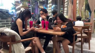 Cep telefonları bir kafede sohbet eden kadın arkadaş grubunda. Dört kadın bir kafede buluşup konuşuyor. Vietnam Da Nang 11.2025