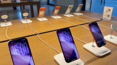 Apple mağazası, modern alışveriş teknolojisi ortamı yaratırken birden fazla iPhone 'un tasarım ve ışıklandırma ekranlarına yerleştirilmiş temiz bir düzenli görüntüsünü gösteriyor. Roma, İtalya 11.25.2025