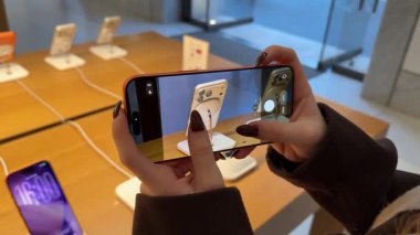 Editör görüntüleri, Apple mağazasında kamera kalitesini yakınlaştırmak ve kontrol etmek için iPhone 17 kullanan kadınların ellerini gösteriyor. Detaylı inceleme berraklığı ve premium akıllı telefon fotoğrafçılık deneyimi. Roma, İtalya 11.25.2025
