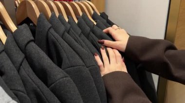 Gardıroptan farklı giysiler seçen, farklı dokuları ve desenleri vurgulayan birinin elleri. Yüksek kalite 4k görüntü