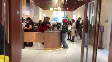 Sahneler Starbucks 'a gelen gençlerin rahatlamak için sırada bekleyip içki içtiğini ve kartlarla ödeme yaptığını gösteriyor. Sosyal ortamda rahatlık ve keyifli bir mola. Roma, İtalya 11.25.2025