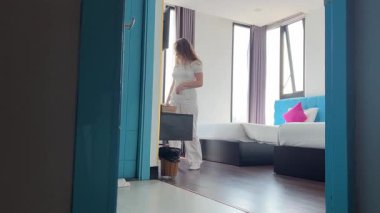 Cep telefonu ekranına bakıp gülen, alışveriş için mobil uygulamalar kullanan, sosyal medyada sohbet eden, ciddi anlamda rahat genç bir kadın kanepeye oturur. .