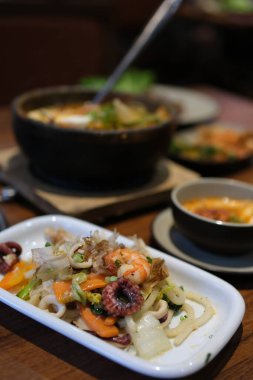 Zarif ve lezzetli bir yemek deneyimi için taze lahanalar ve otlarla süslenmiş makarna yatağında karides bulunan bir gurme deniz ürünleri yemeği. Yüksek kalite fotoğraf