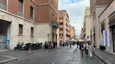Roma 'da Vatikan yakınlarındaki caddelerde gezen turistler, tarihi cephelerin yanında yemek yiyor ve sırada bekliyorlar. İtalyan mimarisi Roma, İtalya 11.30. 2025