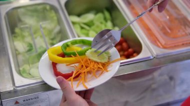 Çalışan, restorandaki sebze istasyonunda renkli bir salata yapıyor. Yavaş çekimde 4K. Yüksek kalite 4k görüntü