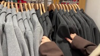 Gri kıyafetlerden renkli kıyafetlere kadar mağazada asılı duran kıyafetlerin yavaş çekim görüntüsü. Yüksek kalite 4k görüntü