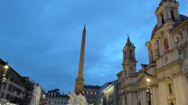 Dört Nehir 'in ikonik Çeşmesi Piazza Navona' nın merkezinde yükselen dikilitaş dinamik mermer figürler ve akan suyla birlikte ziyaretçiler canlı ve tarihi Roma atmosferinin tadını çıkarıyorlar.
