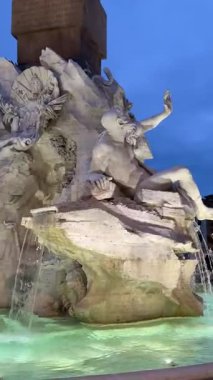 Dört Nehir 'in ikonik Çeşmesi Piazza Navona' nın merkezinde yükselen dikilitaş dinamik mermer figürler ve akan suyla birlikte ziyaretçiler canlı ve tarihi Roma atmosferinin tadını çıkarıyorlar.